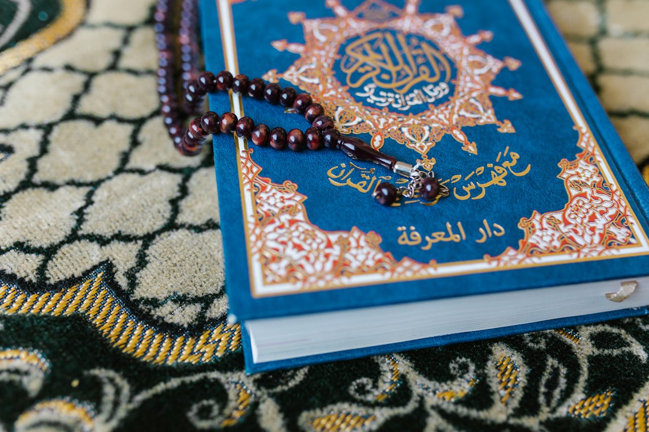 our-services-3 A Quran with prayer beads on a decorative carpet, symbolizing Islamic spirituality.